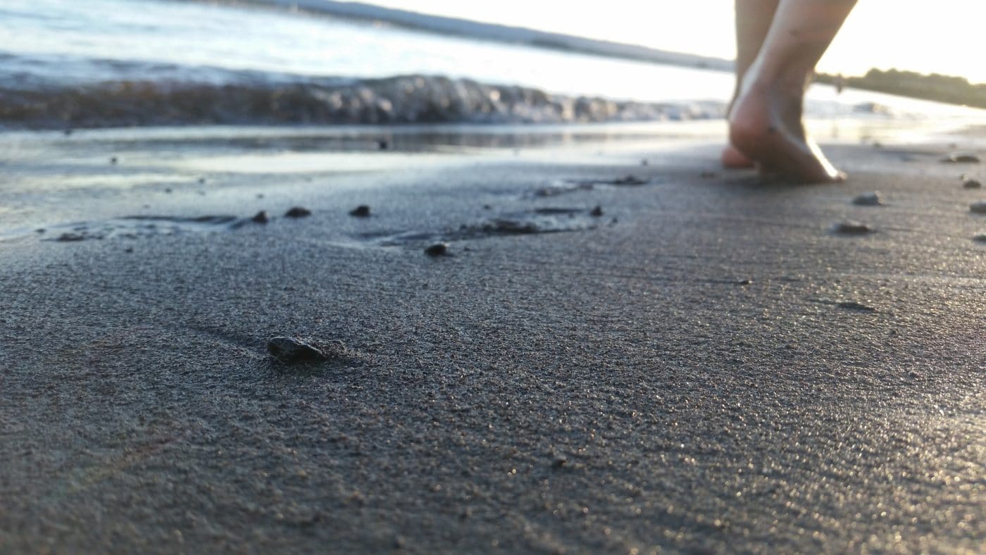 Eine Person läuft barfuß auf einem Sandstrand
