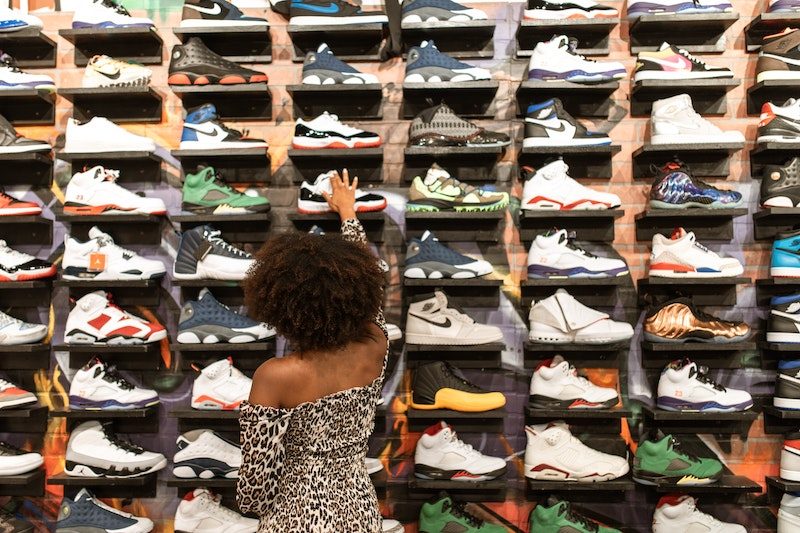 Eine Frau steht vor einer Wand voller Schuhe