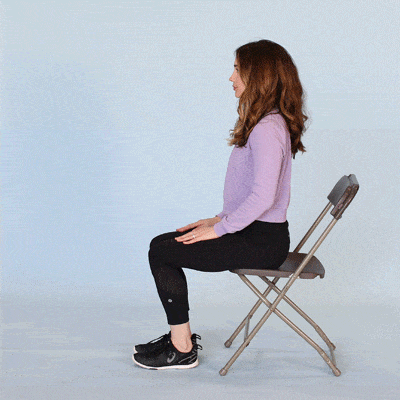 Eine junge Frau sitzt auf einem Stuhl und demonstriert die Knie-Übung Beinhebungen