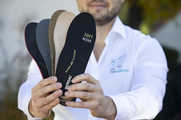 Frank Hepper hält Schuheinlagen verschiedener Hersteller in den Händen