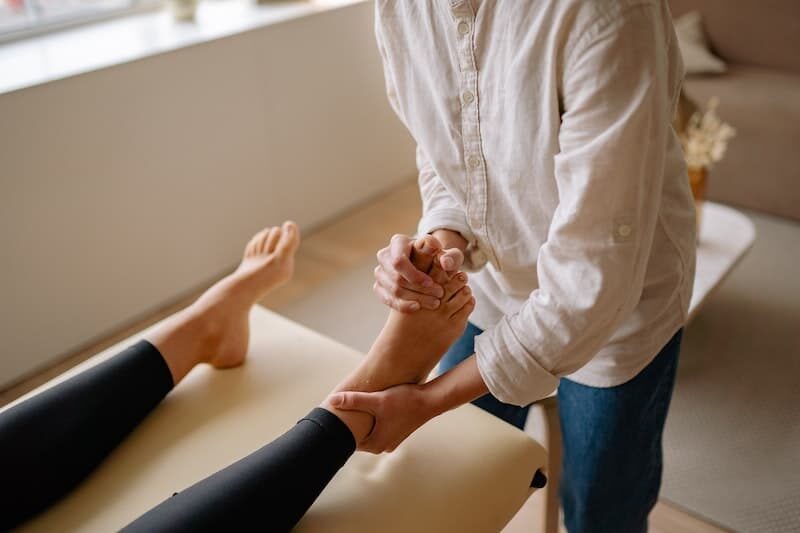 Eine Physiotherapeutin massiert einer Frau die Füße